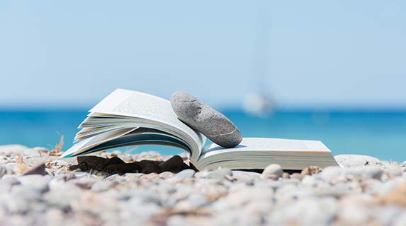 book on the beach with a rock keeping it open